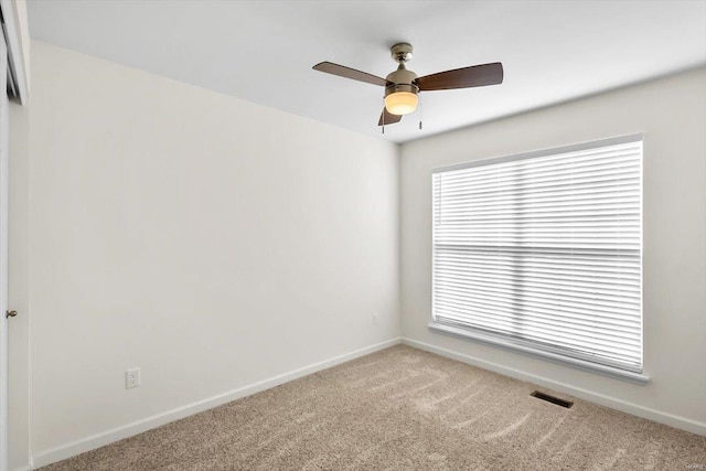 carpeted empty room with a ceiling fan, visible vents, and baseboards