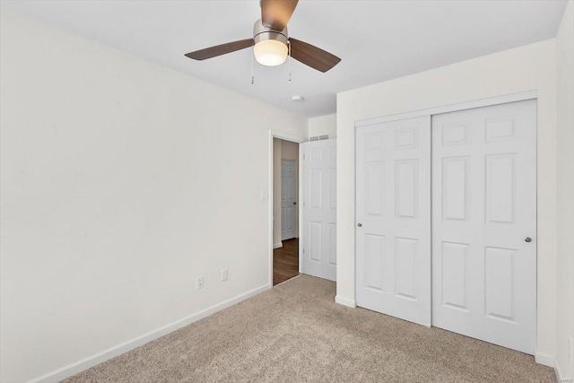 unfurnished bedroom with carpet floors, a closet, a ceiling fan, and baseboards