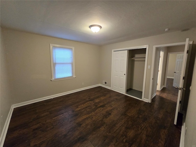 unfurnished bedroom with baseboards, a closet, visible vents, and dark wood-type flooring