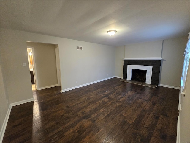 unfurnished living room featuring dark wood-type flooring, a fireplace, visible vents, and baseboards