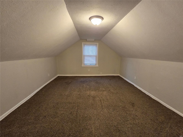 bonus room with vaulted ceiling, a textured ceiling, dark carpet, and baseboards