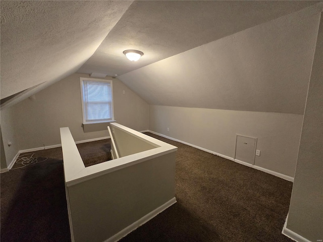 bonus room featuring lofted ceiling, dark carpet, a textured ceiling, and baseboards