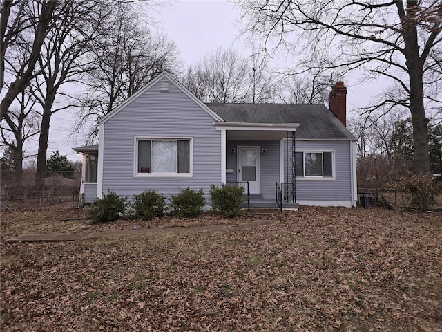 view of front of property with a shingled roof and a chimney