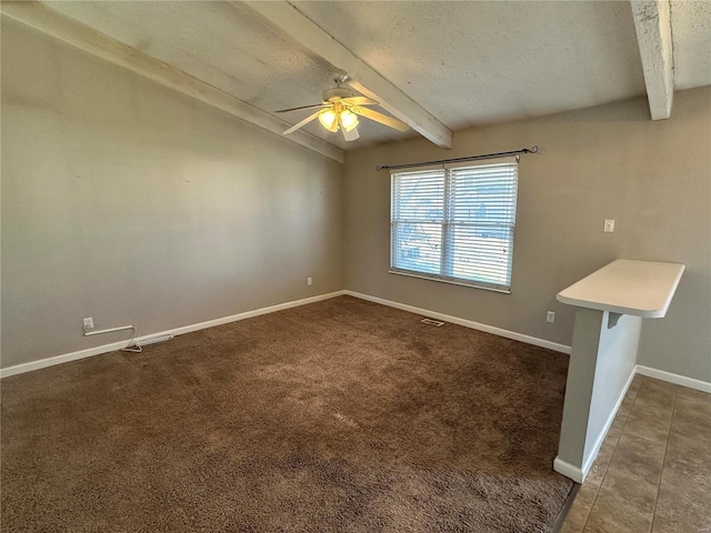 unfurnished room featuring vaulted ceiling with beams, dark colored carpet, ceiling fan, a textured ceiling, and baseboards