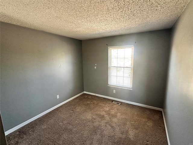 unfurnished room featuring baseboards, visible vents, dark carpet, and a textured ceiling