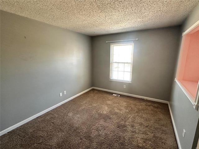 spare room with visible vents, baseboards, dark colored carpet, and a textured ceiling