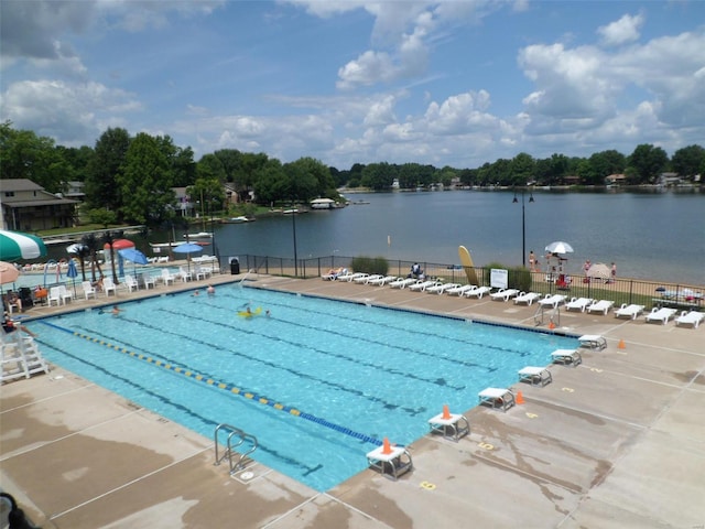 pool with a water slide, a water view, fence, and a patio