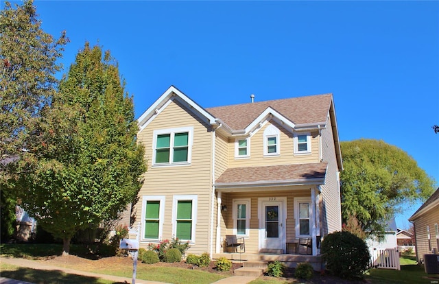 view of front of house featuring covered porch, roof with shingles, and a front yard