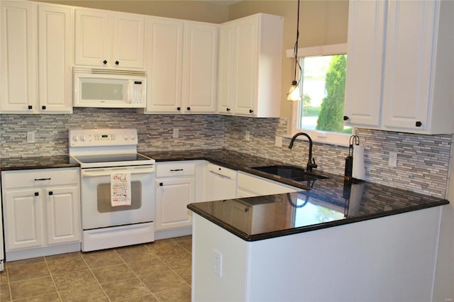 kitchen featuring a peninsula, white appliances, a sink, white cabinetry, and tasteful backsplash