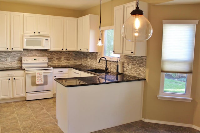 kitchen with white appliances, dark countertops, a sink, a healthy amount of sunlight, and backsplash