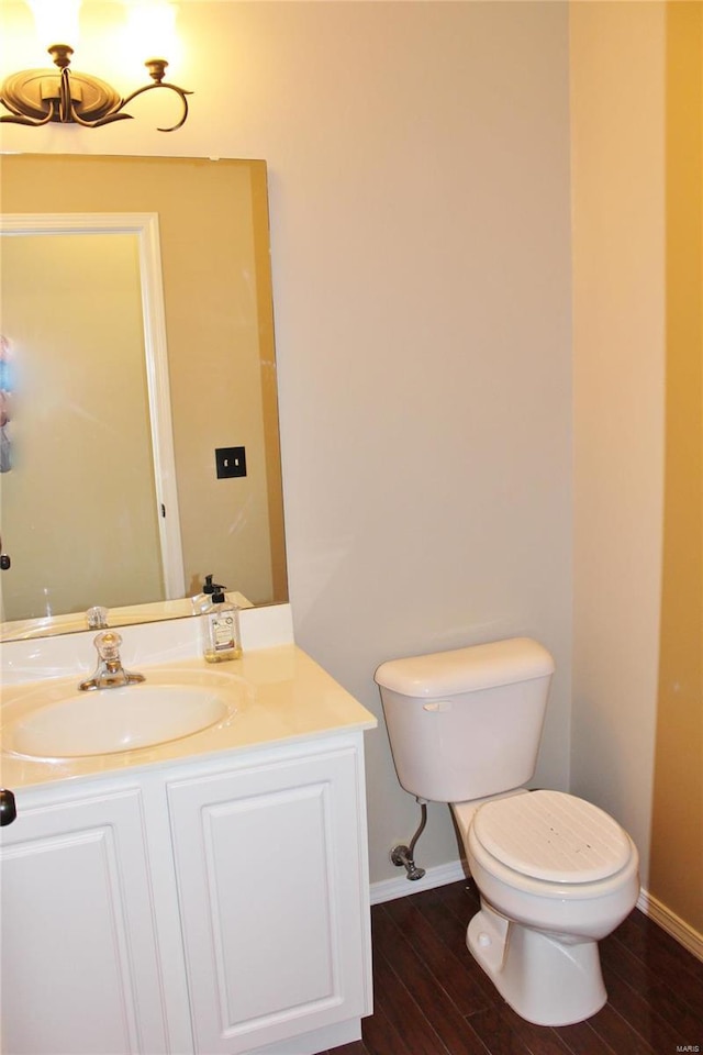 half bathroom with toilet, baseboards, wood finished floors, and vanity