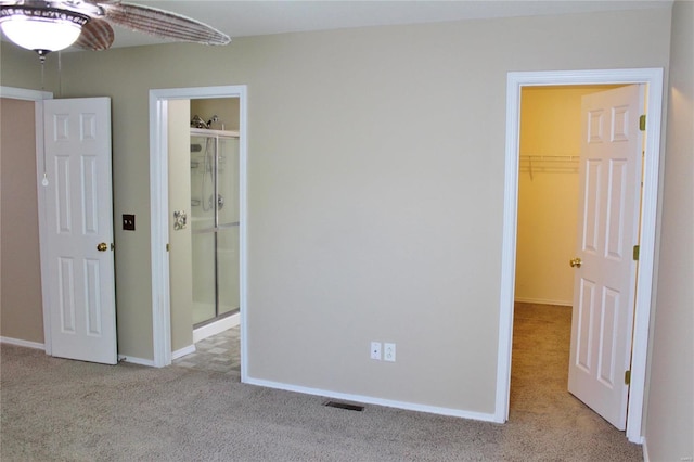 unfurnished bedroom with a closet, visible vents, a spacious closet, carpet flooring, and baseboards