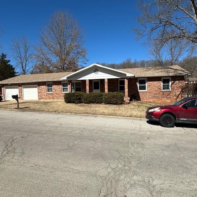 single story home featuring an attached garage and brick siding