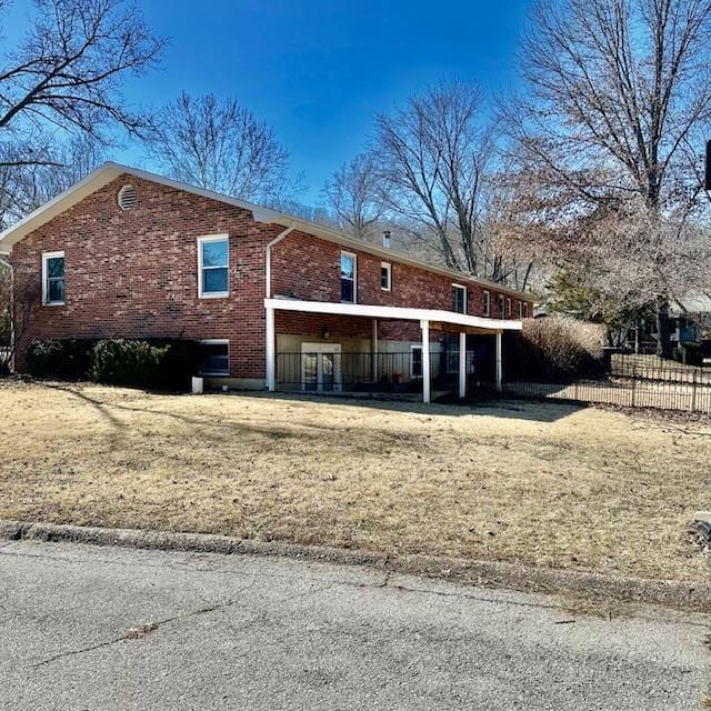 exterior space featuring a front yard, brick siding, and fence