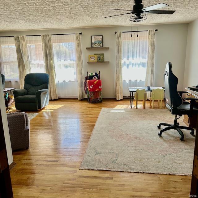 office area featuring a healthy amount of sunlight, ceiling fan, a textured ceiling, and wood finished floors