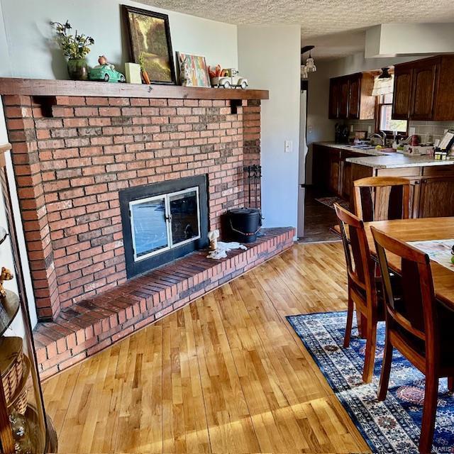 dining room featuring light wood-style flooring, a fireplace, and a textured ceiling