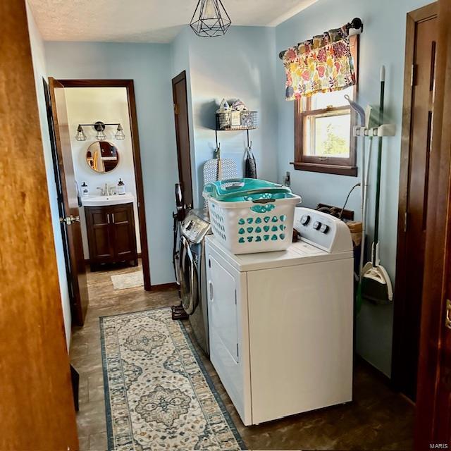 washroom with laundry area, washer and clothes dryer, and a sink