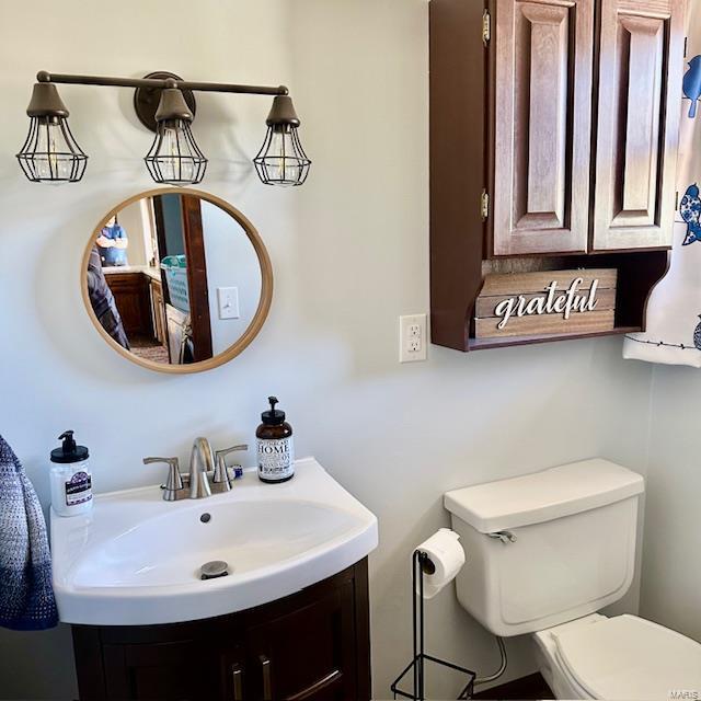 half bathroom featuring vanity and toilet