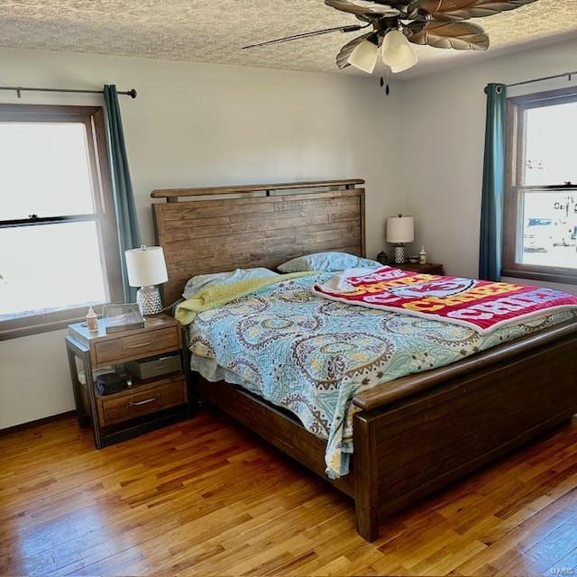 bedroom featuring light wood-style floors, a textured ceiling, and a ceiling fan