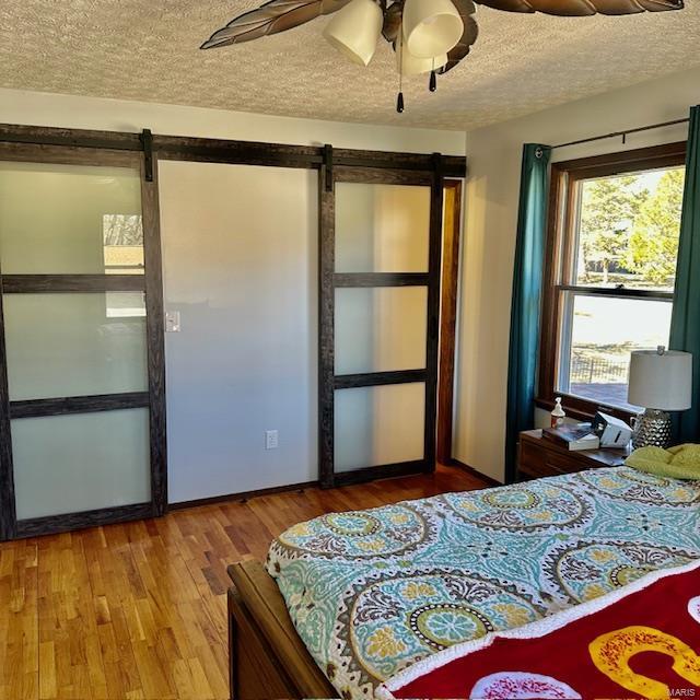 bedroom with ceiling fan, a textured ceiling, and wood finished floors