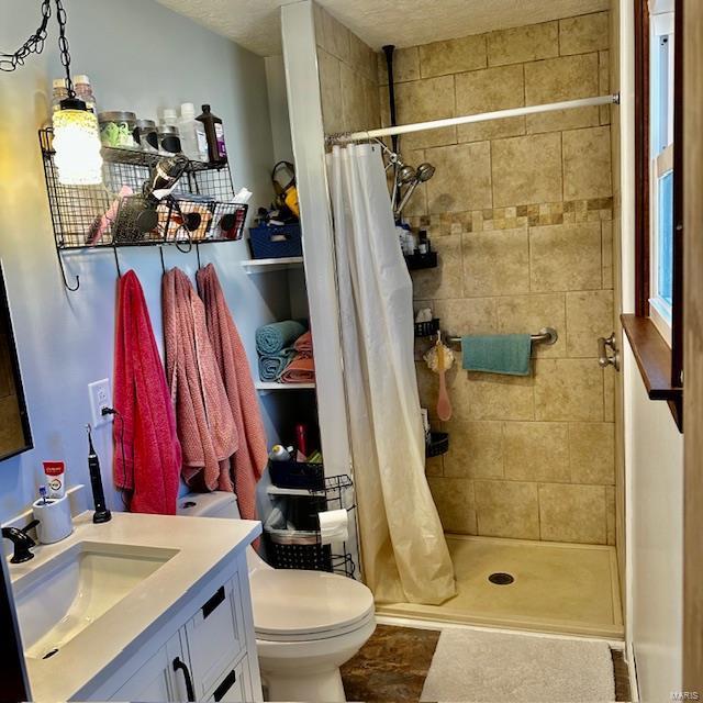 full bath featuring toilet, a textured ceiling, a shower stall, and vanity