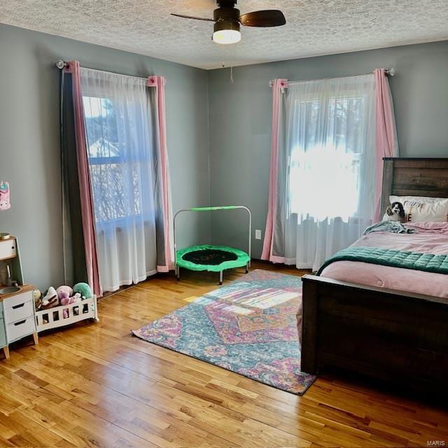 bedroom featuring a ceiling fan, a textured ceiling, and wood finished floors