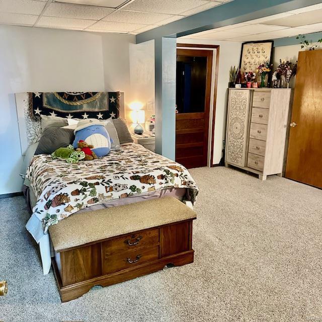 carpeted bedroom with a paneled ceiling and baseboards