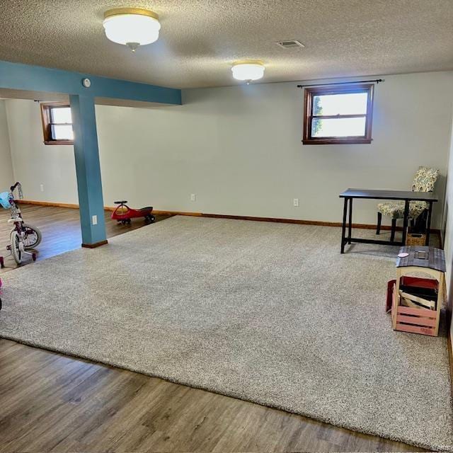 below grade area featuring plenty of natural light, visible vents, and wood finished floors