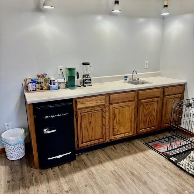 bar with a sink and light wood-style flooring