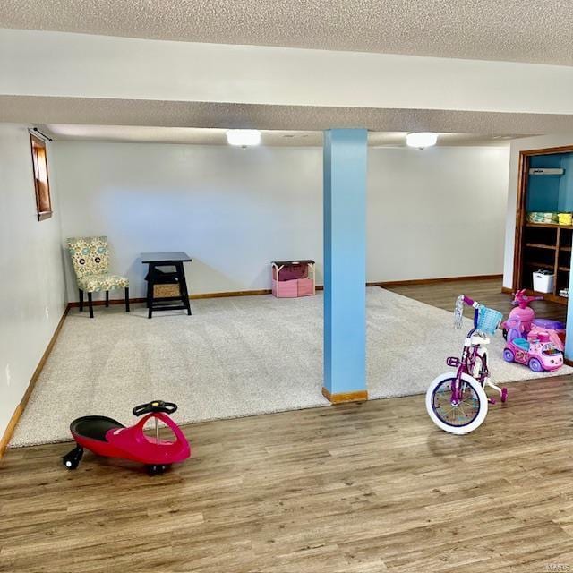 game room with a textured ceiling, baseboards, and wood finished floors