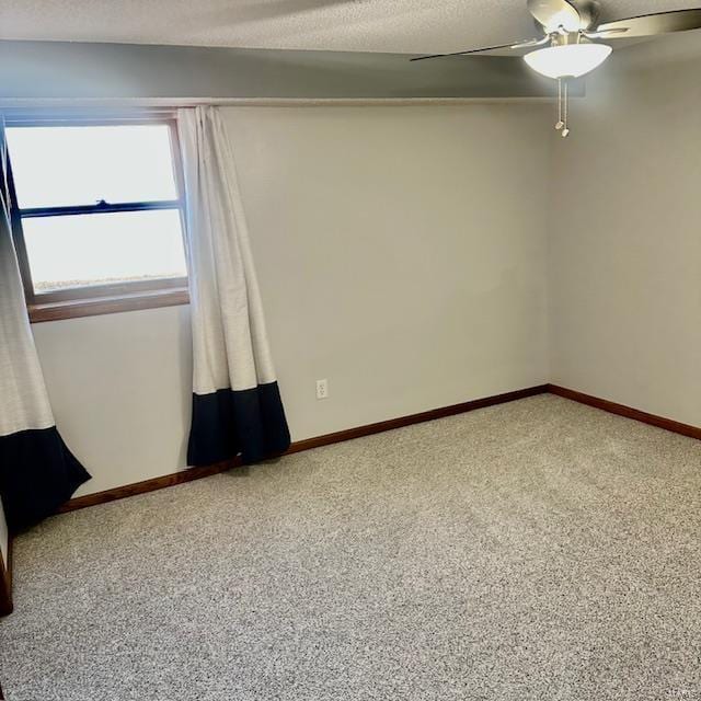 carpeted empty room featuring a textured ceiling, a ceiling fan, and baseboards