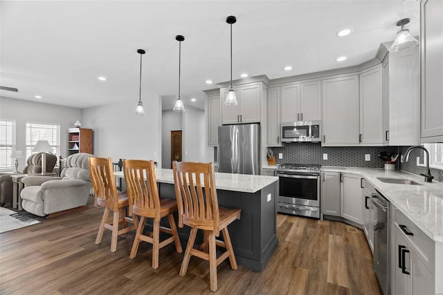 kitchen with light stone countertops, tasteful backsplash, appliances with stainless steel finishes, and a sink