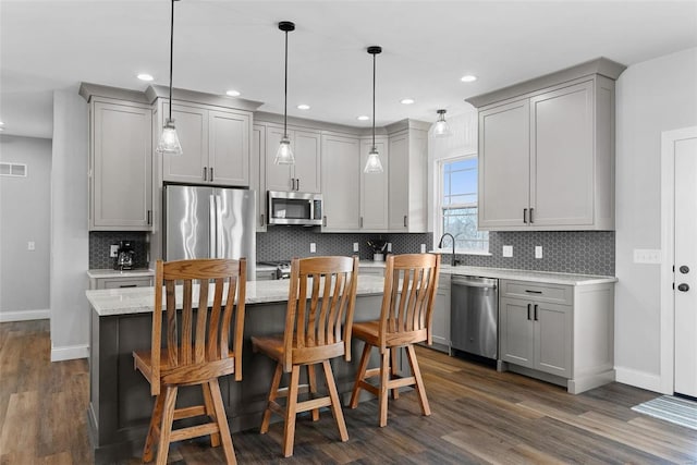 kitchen with a sink, backsplash, appliances with stainless steel finishes, and gray cabinetry