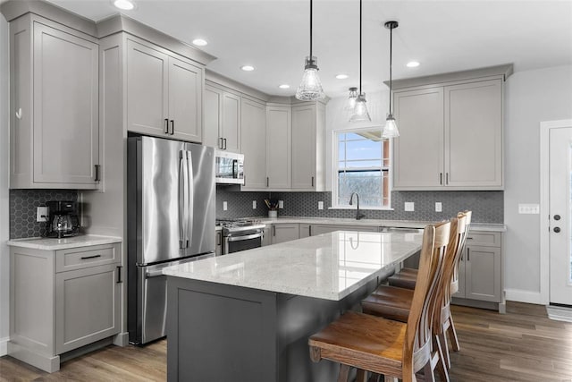 kitchen with a kitchen island, gray cabinets, stainless steel appliances, and wood finished floors