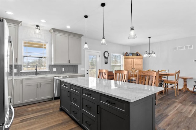 kitchen featuring visible vents, dark wood finished floors, decorative backsplash, stainless steel appliances, and a sink