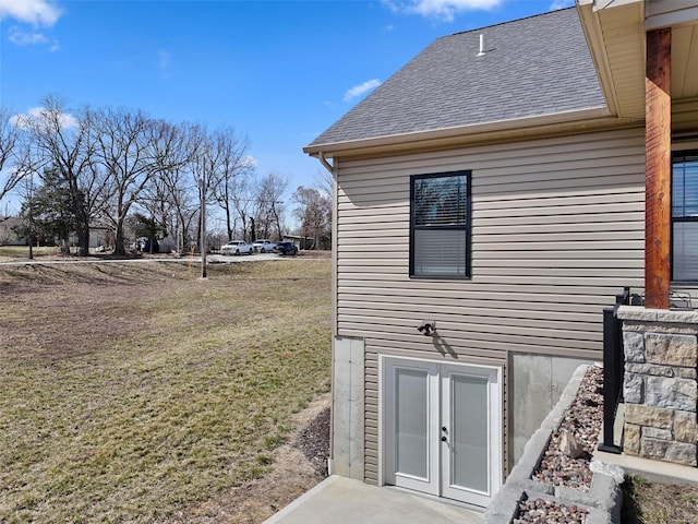 view of side of home with a lawn and a shingled roof