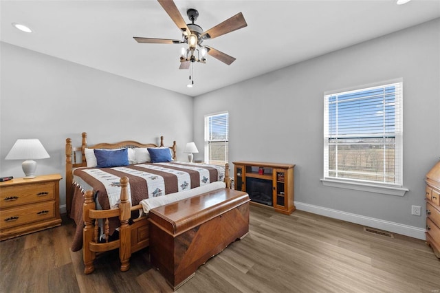 bedroom featuring a ceiling fan, wood finished floors, visible vents, and baseboards