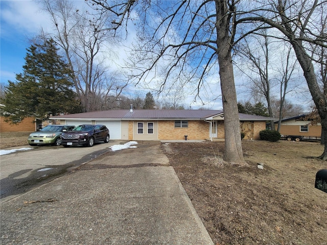 ranch-style house featuring metal roof, driveway, and brick siding