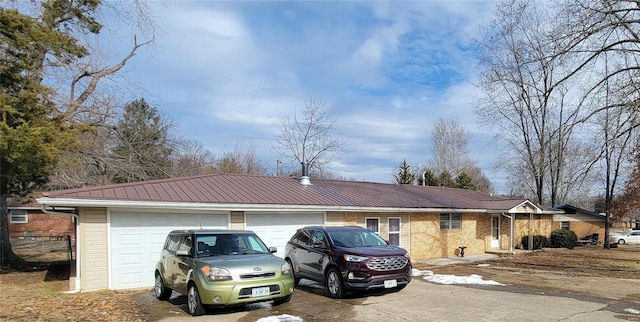 view of front of home with metal roof, concrete driveway, brick siding, and fence