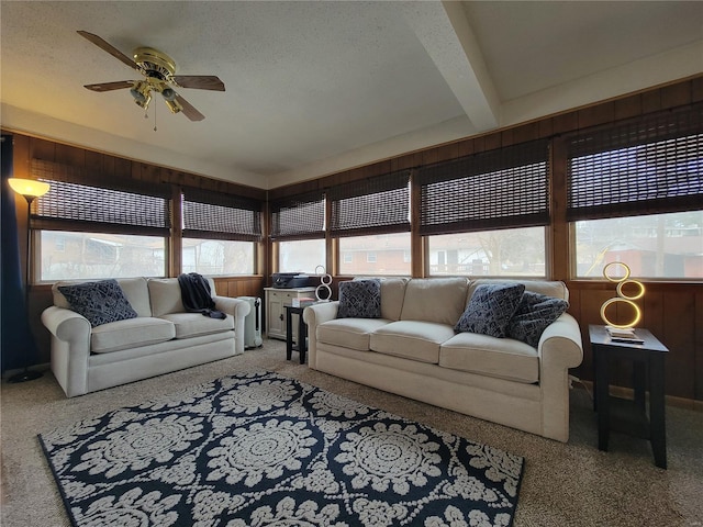 carpeted living room with a textured ceiling, a ceiling fan, and beamed ceiling