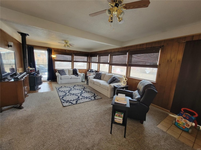 living room with wood walls, a wood stove, and light colored carpet