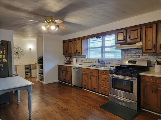 kitchen with dark wood-style floors, stainless steel appliances, light countertops, under cabinet range hood, and backsplash