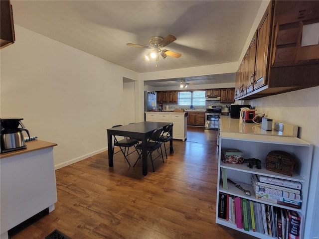 dining space featuring dark wood-style floors, baseboards, and a ceiling fan