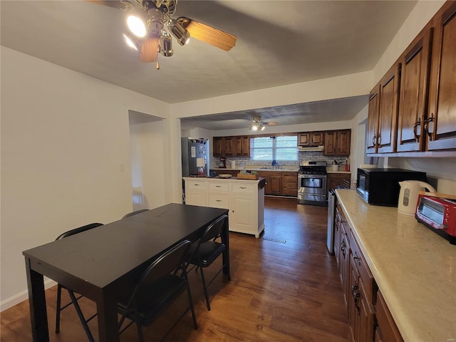 kitchen featuring tasteful backsplash, gas range, dark wood-style flooring, under cabinet range hood, and black microwave