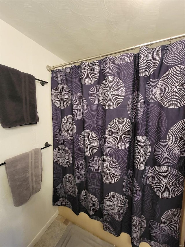 bathroom with curtained shower and baseboards