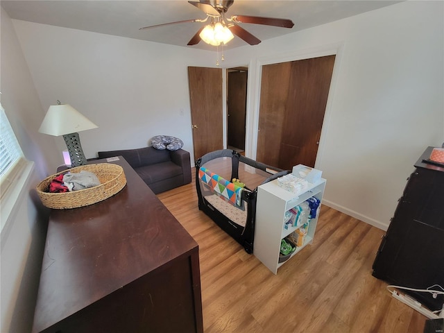 interior space featuring a ceiling fan, light wood-style flooring, and baseboards