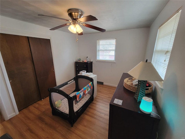 bedroom with baseboards, a closet, a ceiling fan, and light wood-style floors