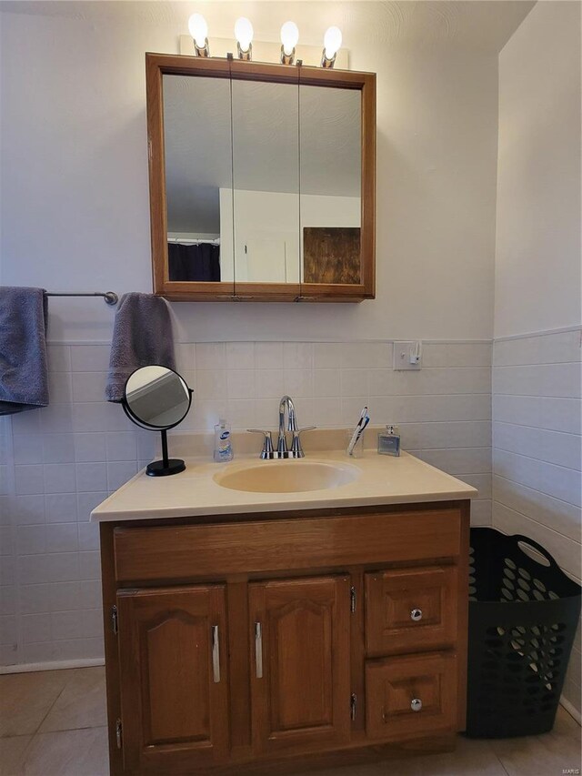 bathroom featuring a wainscoted wall, tile patterned flooring, tile walls, and vanity