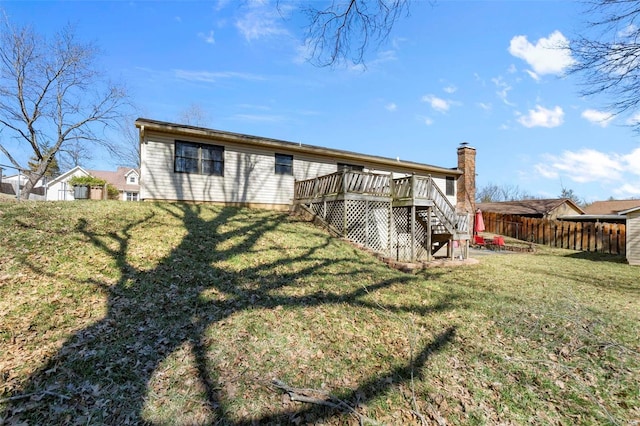 rear view of house featuring fence, stairway, a wooden deck, and a lawn