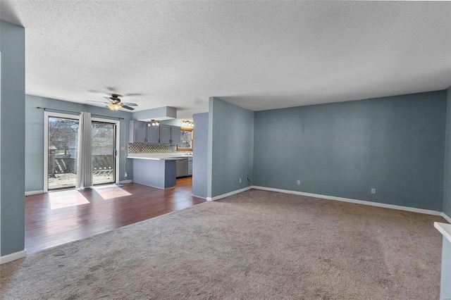 unfurnished living room with dark colored carpet, ceiling fan, a textured ceiling, and baseboards